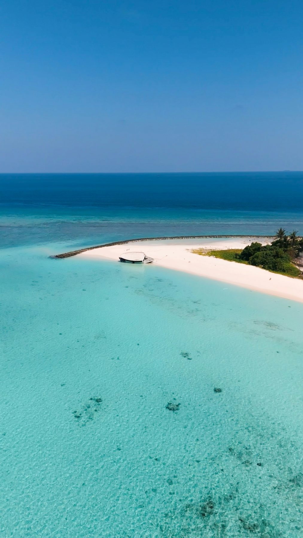 Aerial view of a boat moored beside a sandy point on Fulidhoo Island, Vaavu Atoll, Maldives