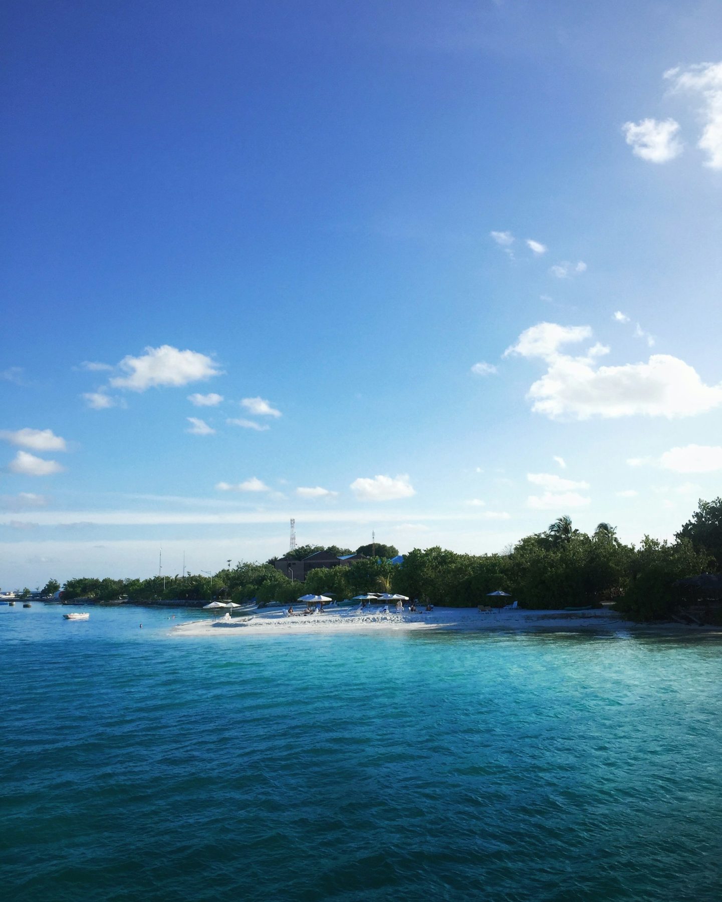 A local-island bikini beach in the Maldives with sun loungers and shade umbrellas by a turquoise lagoon (representative photo, not Gulhi itself)