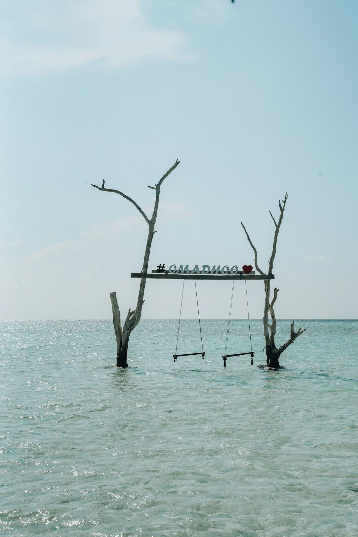 Swing seats over shallow turquoise water, a classic Maldives beach scene (representative photo, not taken at Omadhoo)