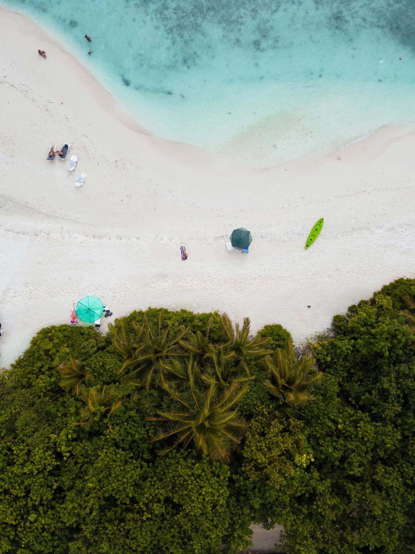 Aerial view of sunbeds, umbrellas and a kayak on the white sand of Bikini Beach, Ukulhas, Maldives